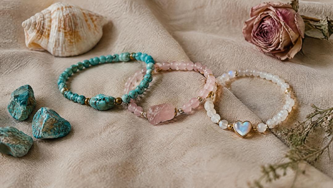 Trois bracelets bohèmes turquoise, rose et blanc disposés sur du lin avec un coquillage